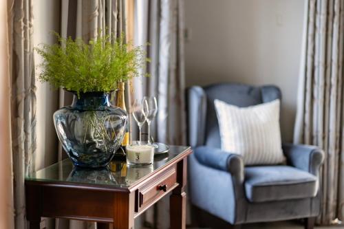 a vase on a table with a blue chair and a vase at Lemoenkloof Boutique Hotel in Paarl
