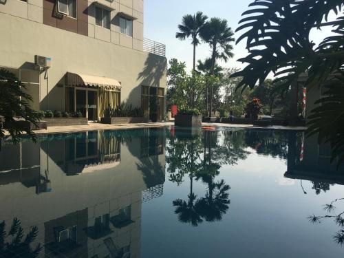 a pool of water in front of a building at Cozy 2BR at Pinewood Apartment By Travelio in Sumedang