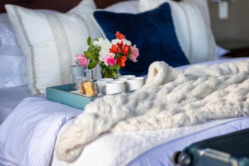 a bed with a tray with a vase of flowers on it at Lemoenkloof Boutique Hotel in Paarl