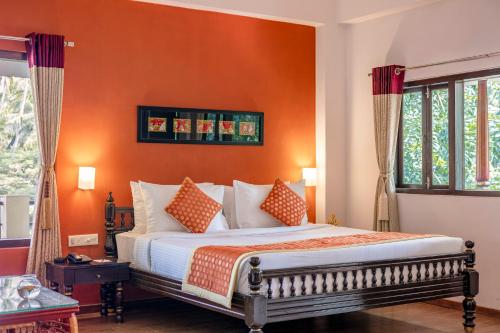 a bedroom with a bed with an orange wall at Sterling Palavelli Godavari in Rāzole