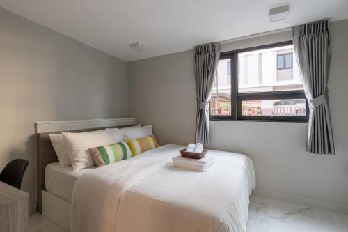 a bedroom with a white bed with a window at CJ ELAND Sukhumvit36 BTS Thonglor in Klong Toi