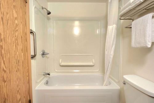 Super 8 by Wyndham Portage La Prairie MB في بورتاج لا بريري: حمام صغير مع حوض استحمام أبيض بجوار مرحاض