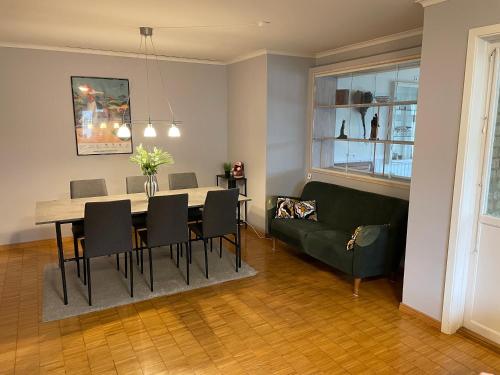 a dining room with a table and a green couch at Stort hus, underbar utsikt & 3 min till Isaberg! in Hestra