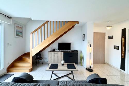 a living room with a staircase and a couch at Joli duplex plein bourg - 4km des plages in Guidel