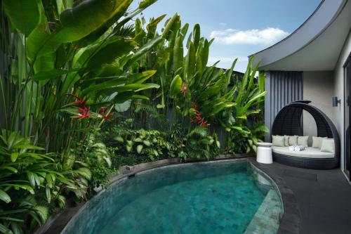 a swimming pool in the middle of a garden at Je Ne Sais Quoi Seminyak in Seminyak