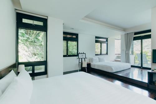 a white bedroom with two beds and large windows at Adagio JinGuaShi in Jiufen