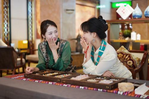 two women sitting at a table looking at cookies at Chengdu Tibetan Hotel-Free Welcome Tibetan Tea in Chengdu