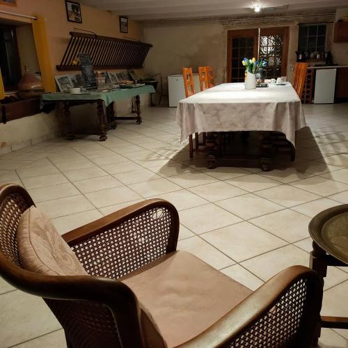 a room with a table and chairs and a tiled floor at La ferme du Grand Faubourg in Pont-de-Vaux