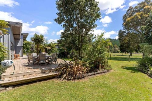 a wooden deck with a table and chairs in a yard at The Grass is Greener Getaway - Private Hot Tub in Whangamata