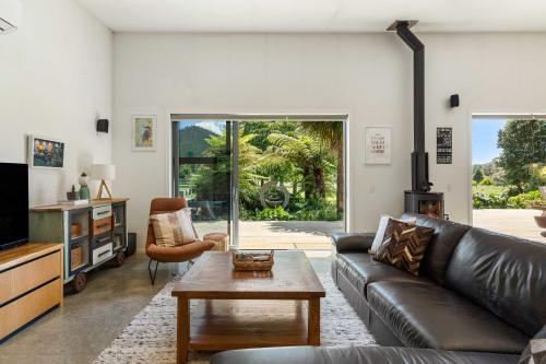 a living room with a leather couch and a table at The Grass is Greener Getaway - Private Hot Tub in Whangamata