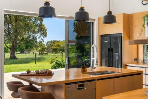 a kitchen with a sink and a large window at The Grass is Greener Getaway - Private Hot Tub in Whangamata