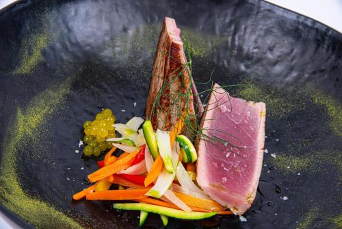 a plate of food with a piece of meat and vegetables at Hotel Europa Lignano in Lignano Sabbiadoro