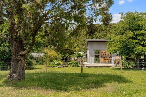 a small shed in a yard with a tree at The Grass is Greener Getaway - Private Hot Tub in Whangamata