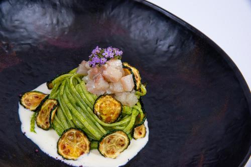 a black plate of food with beans and vegetables at Hotel Europa Lignano in Lignano Sabbiadoro