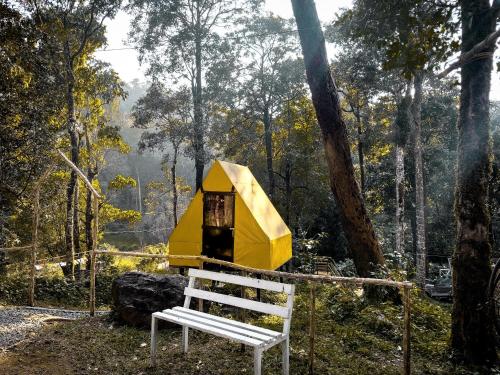 a yellow tent with a white bench in front of it at Skyfall 900kandi in Meppādi
