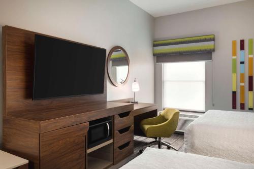 a hotel room with a flat screen tv on a dresser at Hampton Inn Starkville in Starkville