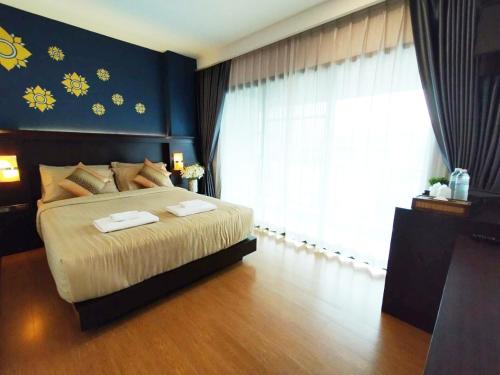 a bedroom with a large bed and a window at Patra Phrasing Boutique Hotel in Chiang Mai