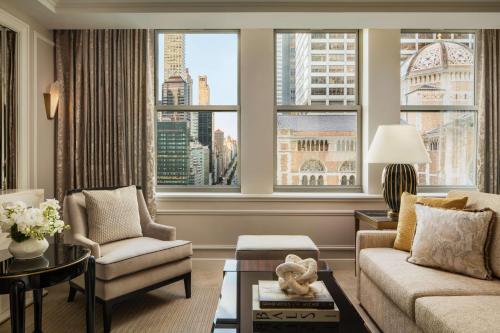 a living room with a couch and chairs and windows at Waldorf Astoria New York in New York