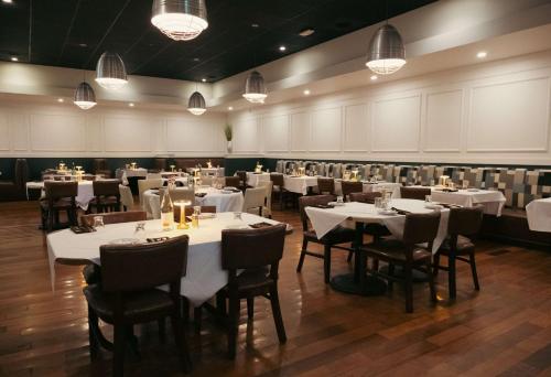 a dining room with white tables and chairs and lights at Hilton Palm Beach PBI in West Palm Beach