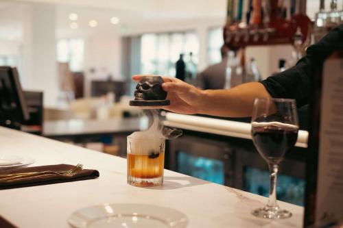 a person is preparing a drink at a bar at Hilton Palm Beach PBI in West Palm Beach