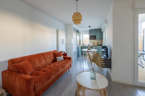 un salon avec un canapé marron et une table dans l'établissement Nid Ensoleillé - A proximité de la plage, à Arcachon