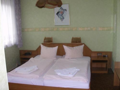 Una cama con sábanas blancas y toallas blancas. en Hotel-Restaurant Marcus en Malchin