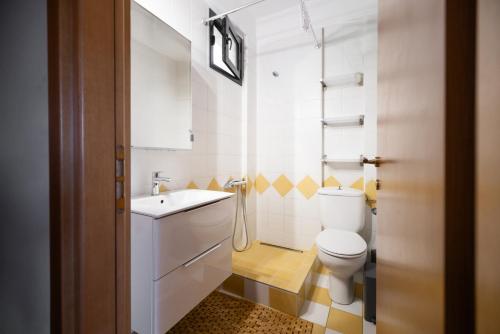 a white bathroom with a toilet and a sink at Pelagos Paradise Seafront Studio by Booking Kottas in Kalamitsi