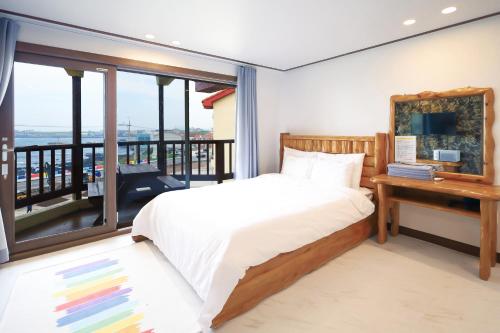 a bedroom with a bed and a balcony at New Coastal Scenery in Jeju