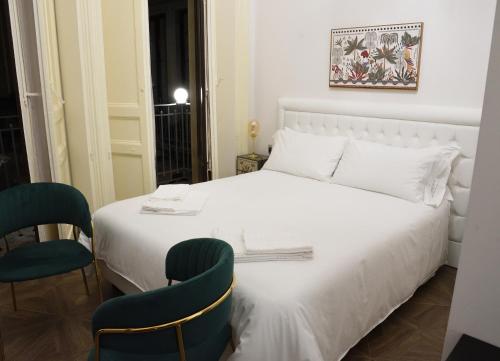 una camera con un letto bianco e due sedie di LN B&B CATANIA a Catania
