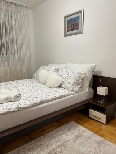 a bedroom with a bed with pillows and a window at Apartman KIKA in Banja Luka