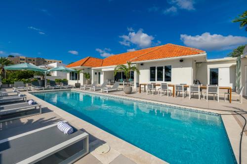 a swimming pool with chairs and a house at LUX 10BR 10BA Pool Beach Front Villa Playa by Bocobay in Oranjestad
