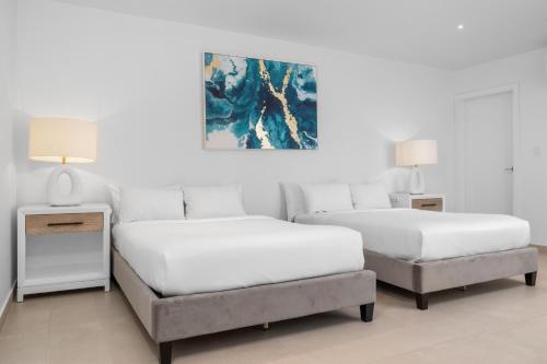two beds in a white room with a bed and a chair at LUX 10BR 10BA Pool Beach Front Villa Playa by Bocobay in Oranjestad