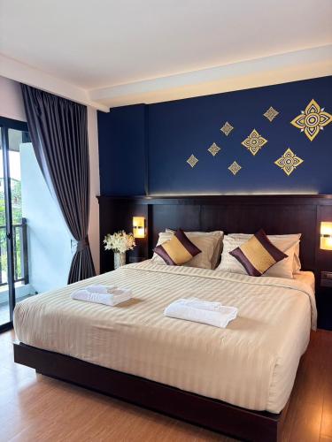 a bedroom with a large bed with a blue wall at Patra Phrasing Boutique Hotel in Chiang Mai