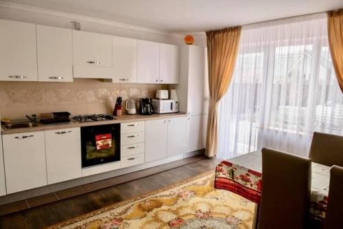 a kitchen with white cabinets and a stove at Casa Rosa in Piatra Neamţ