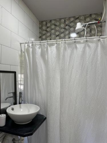 a bathroom with a white shower curtain and a sink at Villa Nola in Port-of-Spain