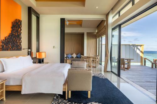 a bedroom with a bed and a balcony at Angsana Velavaru in Dhaalu Atoll