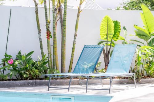 two blue chairs sitting next to a swimming pool at Oasis du Lagon - Villa Hugo in Saint-Gilles les Bains