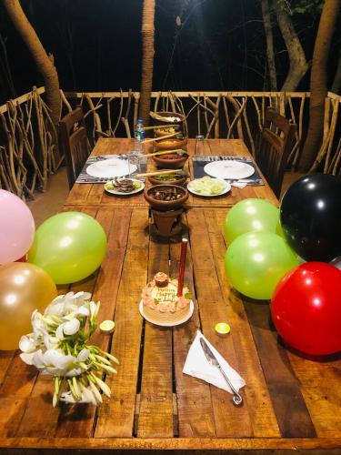 a wooden table with balloons and plates of food on it at Jungle Shades villa - Habarana in Habarana