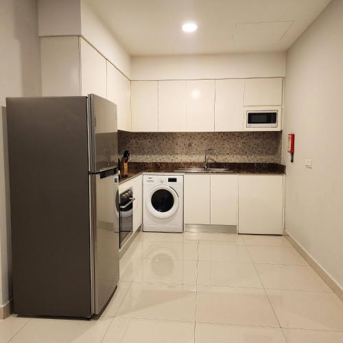a kitchen with a refrigerator and a washing machine at JUFFAIR BOULEVARD HOTEL & SUITES in Juffair