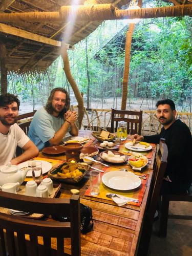 a group of men sitting around a table with food at Jungle Shades villa - Habarana in Habarana
