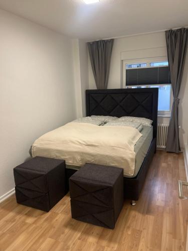 Un dormitorio con una cama grande con dos taburetes. en Apartment Paris, WIFI, CITY, en Krefeld