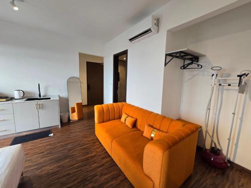 a living room with an orange couch in a room at K Avenue Kota Kinabalu by Merveille - Sabah in Donggongon