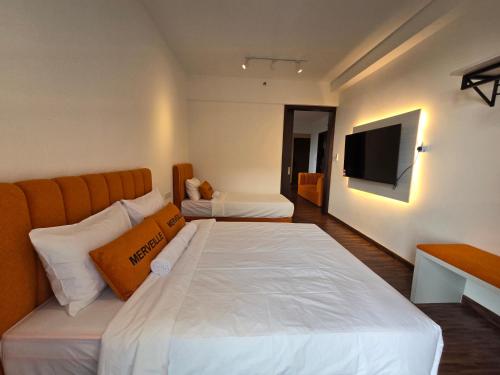 a bedroom with two beds and a television on the wall at K Avenue Kota Kinabalu by Merveille - Sabah in Donggongon