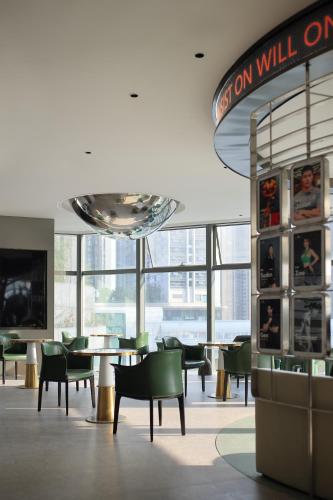 a dining room with tables and chairs and a television at Grand Mercure Shenzhen Guangming in Shenzhen