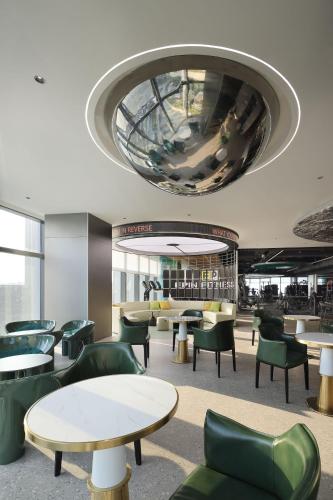 a waiting room with tables and green chairs at Grand Mercure Shenzhen Guangming in Shenzhen