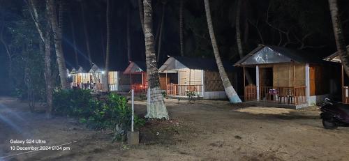 a row of wooden huts in the woods at night at Jungle Beach Resort in Neil Island
