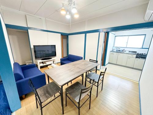 a dining room with a table and chairs and a tv at まるとくハウス都城谷頭 in Miyakonozyō