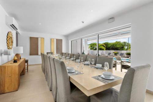 a dining room with a long table and chairs at LUX 10BR 10BA Pool Beach Front Villa Playa by Bocobay in Oranjestad