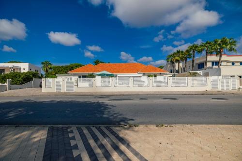 a house with an orange roof and white fence at LUX 10BR 10BA Pool Beach Front Villa Playa by Bocobay in Oranjestad