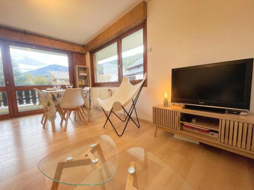 un salon avec une télévision et une table avec des chaises dans l'établissement Appartement rénové au centre du village avec balcon et accès skibus - FR-1-624-145, à Samoëns